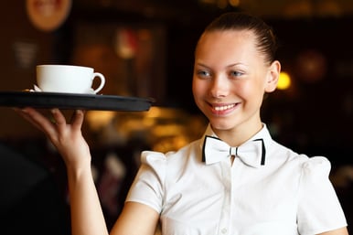 Portrait of young waitress in white blouse holding a tray